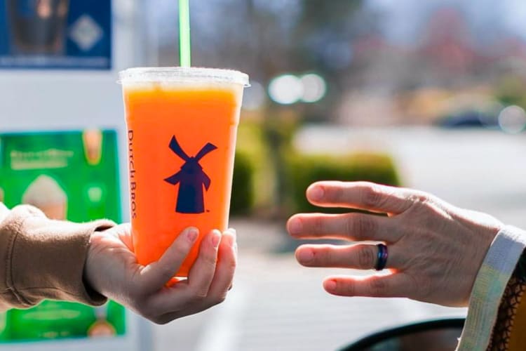 A person handing an orange drink to another person