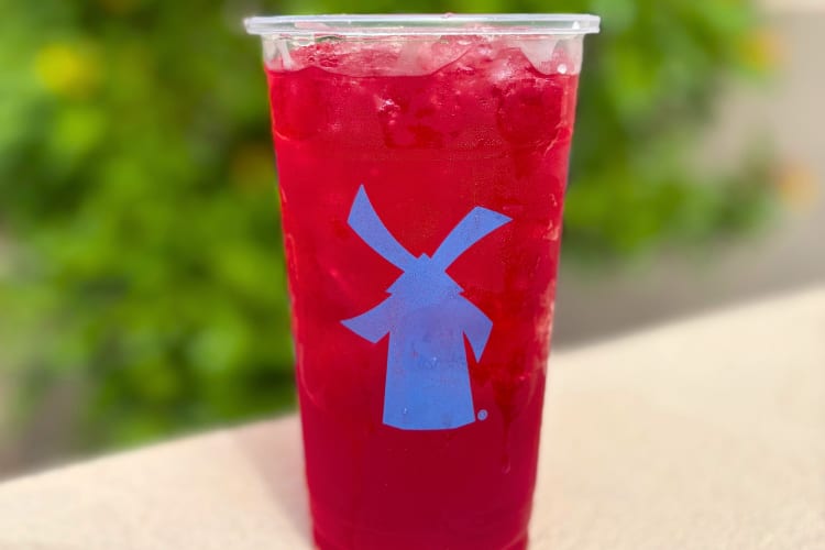 A red drink in a clear Dutch Bros cup with a blue windmill