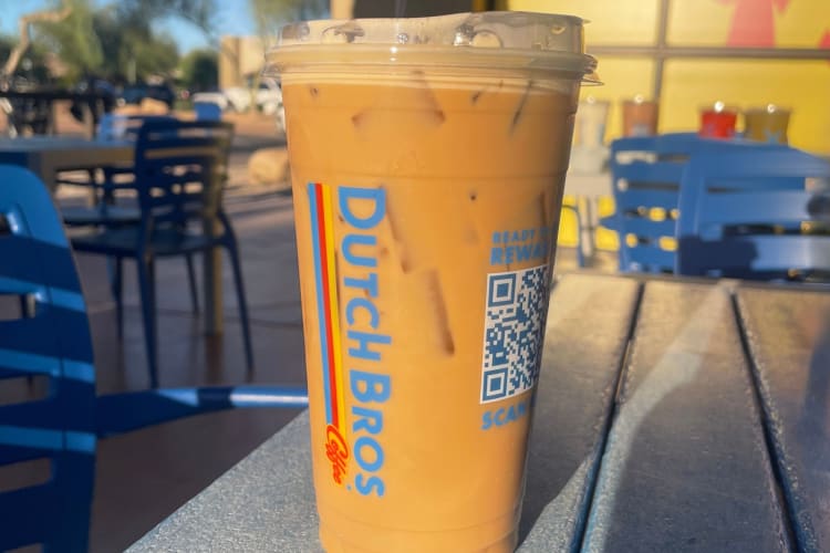 A nitro cold brew drink from Dutch bros on a table outside