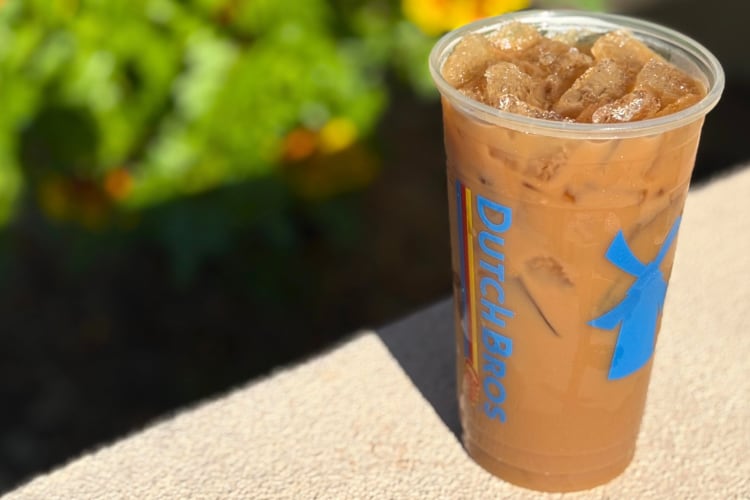 An iced coffee from Dutch Bros on a wall outside