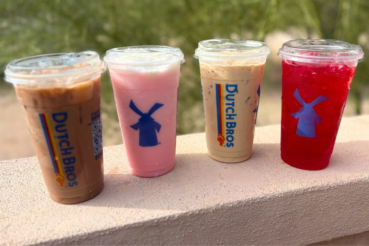 Four different Dutch Bros drinks on a wall outside