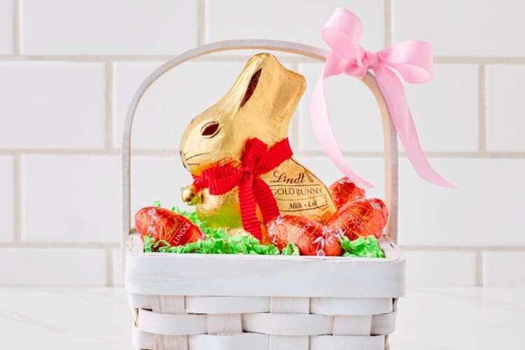 A gold-wrapped chocolate bunny in a white basket