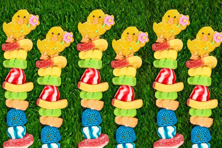 Easter themed gummy kabobs in a line on the grass