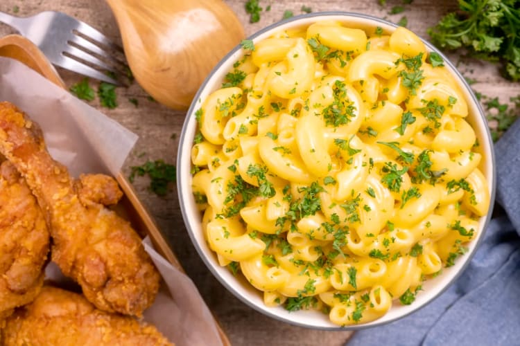 A bowl of mac and cheese next to fried chicken