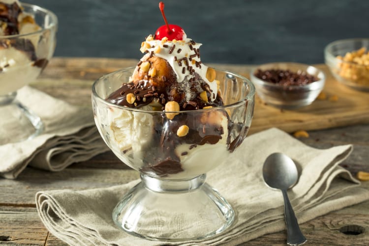 An ice cream sundae with chocolate sauce, peanuts and a cherry