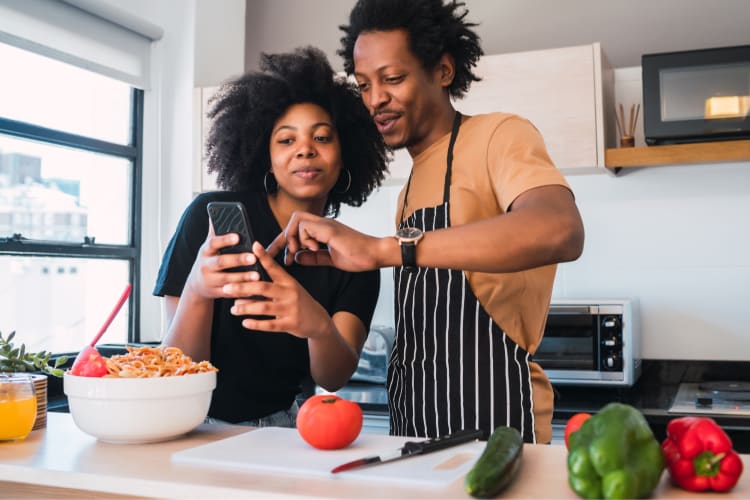 A couple cooking and looking at a phone screen