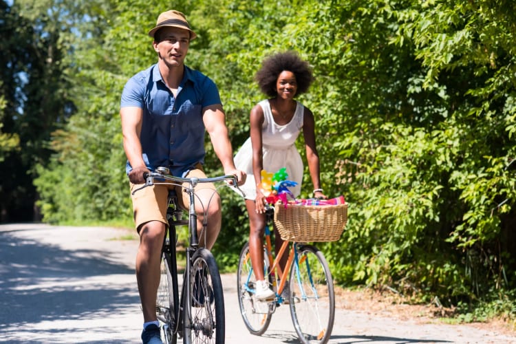 A couple biking on a tree-lined road