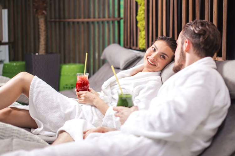 A couple on loungers in white robes at a spa