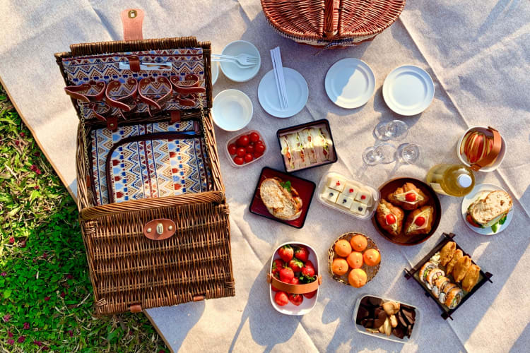 A picnic hamper and food on a blanket