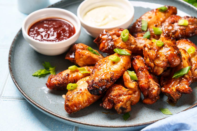 A plate of chicken wings with ketchup and mayo