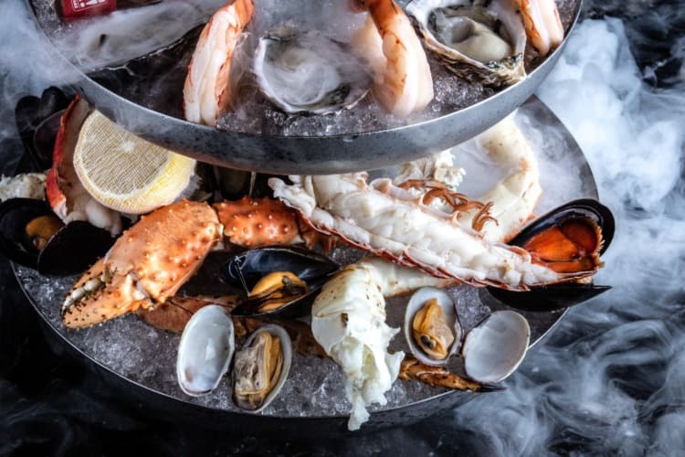 A seafood tower with dry ice clouds around it