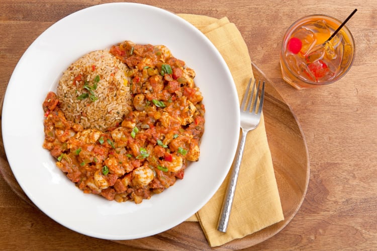 A plate of jambalaya next to a cocktail