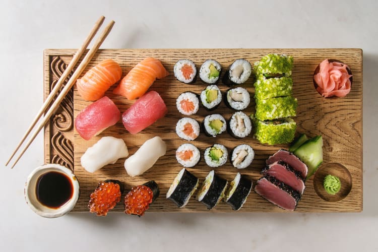 A range of sushi rolls on a wooden serving platter