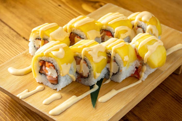 Sushi rolls with mango on a wooden serving tray