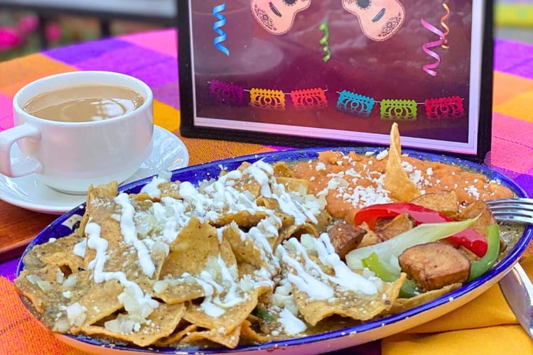 Nachos on a plate with sauce and vegetables, next to a coffee, from El Patio Restaurant