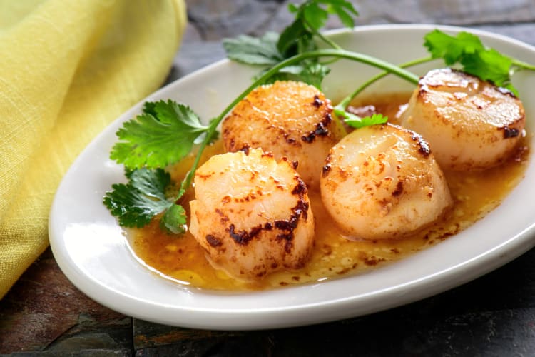 Scallops in a white bowl with garnish on top