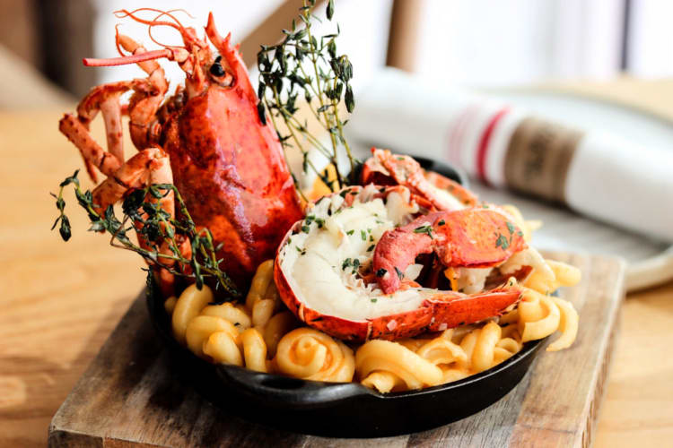 Lobster mac and cheese with a whole lobster in a skillet