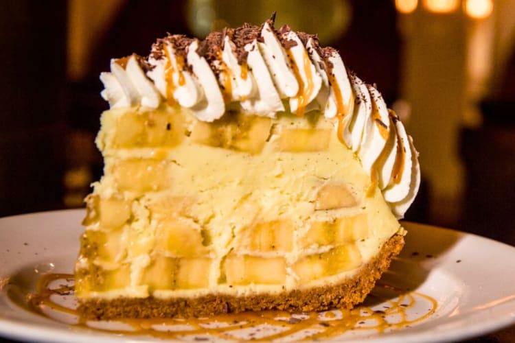 A slice of pie with ice cream, bananas and whipped cream