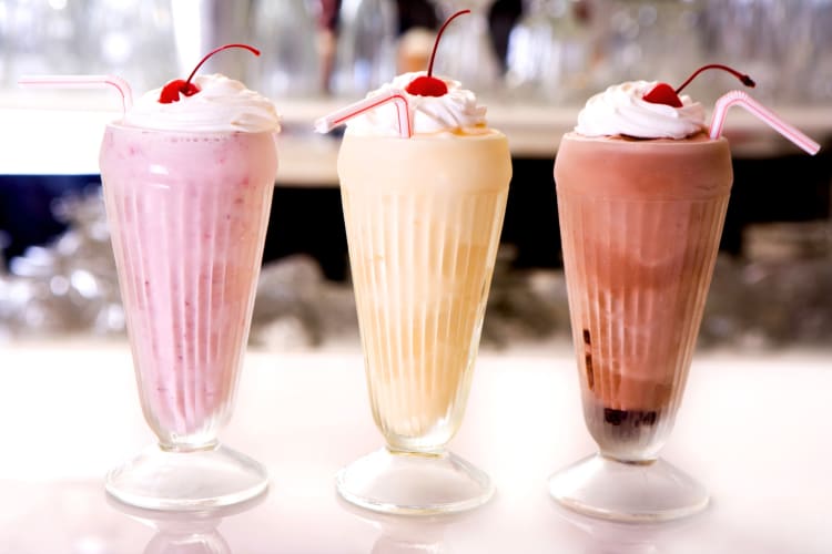Chocolate, strawberry adnd vanilla milkshakes on a counter