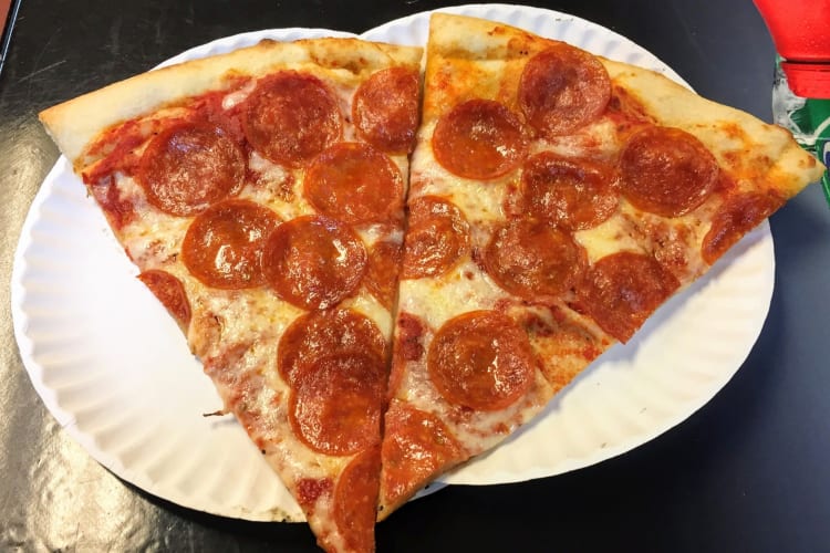 Two slices of pepperoni pizza on paper plates