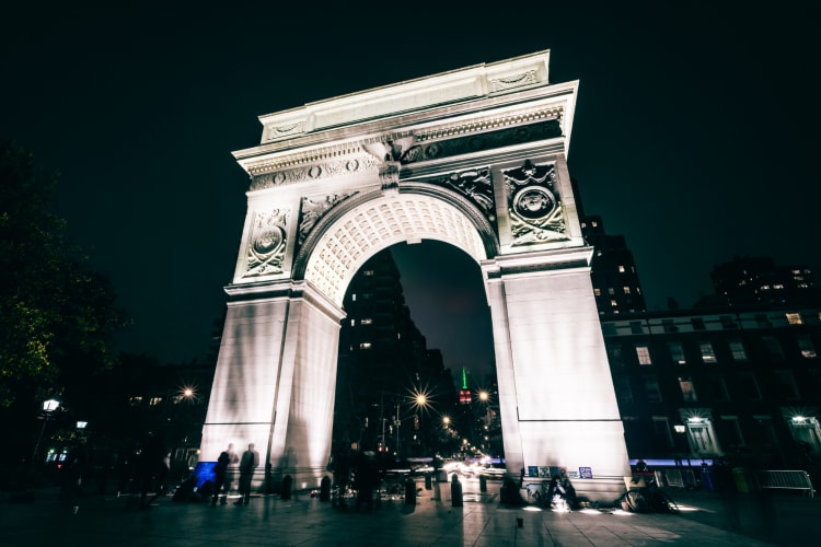 A stone arch in a square at night