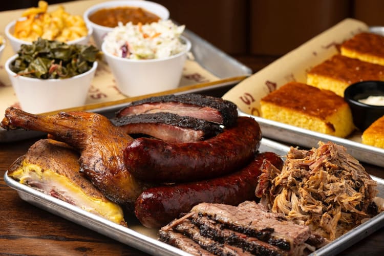 Barbecued meats, sides and cornbread on a table