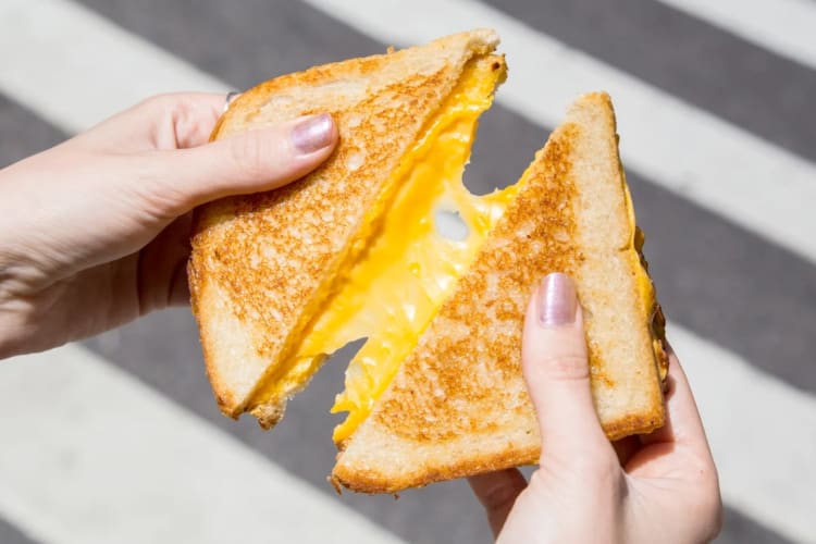 A person holding a grilled cheese from Melt Shop NYC