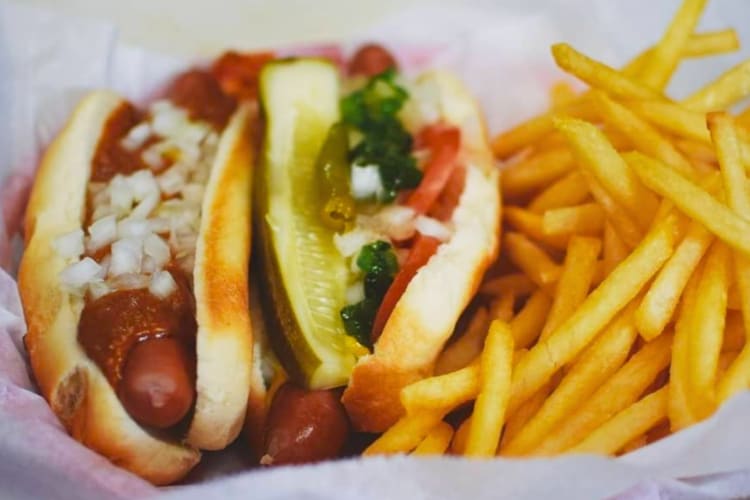 A chili dog next to fries and pickles