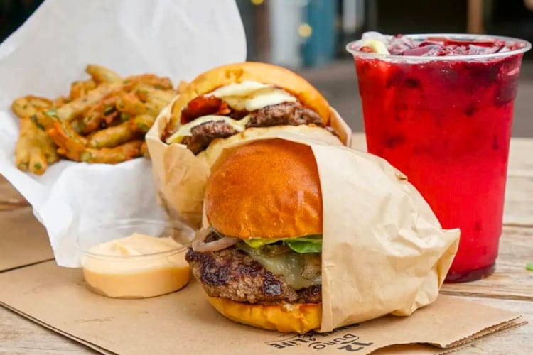 Two burgers and fries next to a red drink