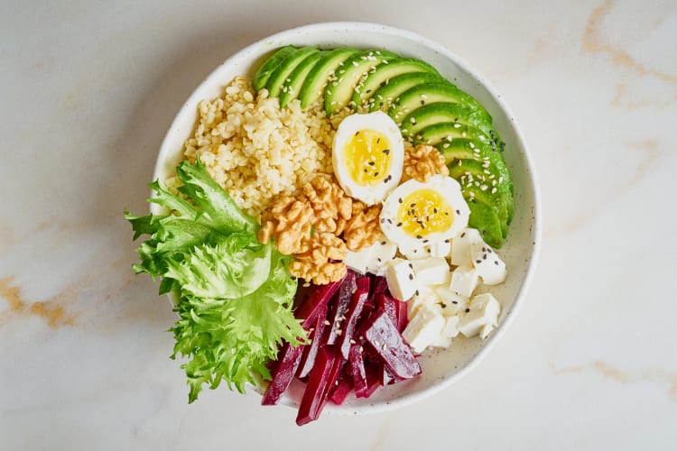 Overhead view of a salad with eggs, beetroot, avocado, feta cheese and greens