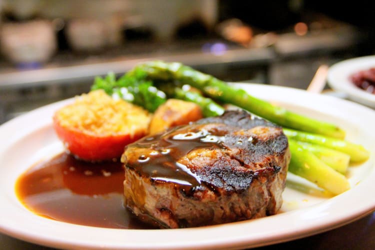 Steak with gravy poured over it, and a side of vegetables