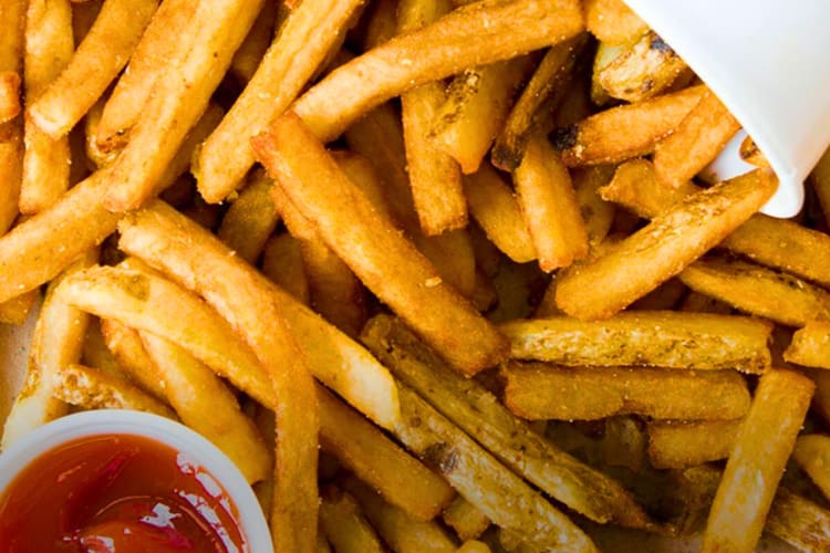 Fries next to a cup and ketchup