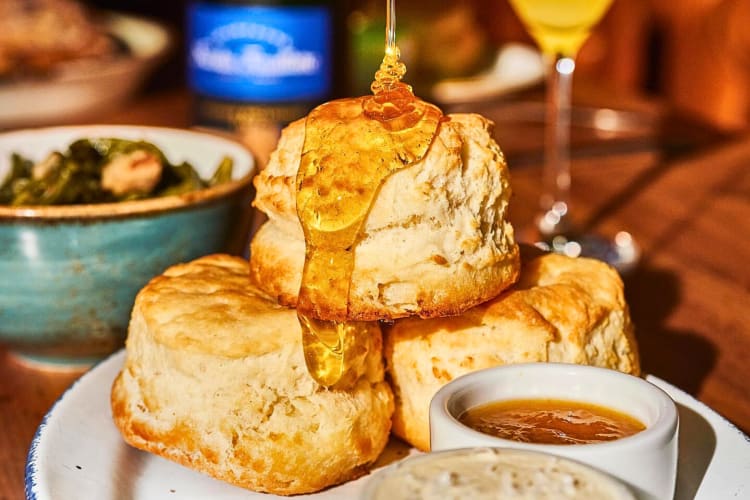 Honey being poured over three biscuits from Fixe Southern House