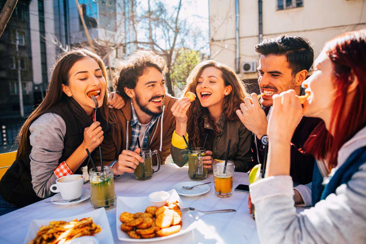 Five friends eating together at the outdoor area of a restaurant