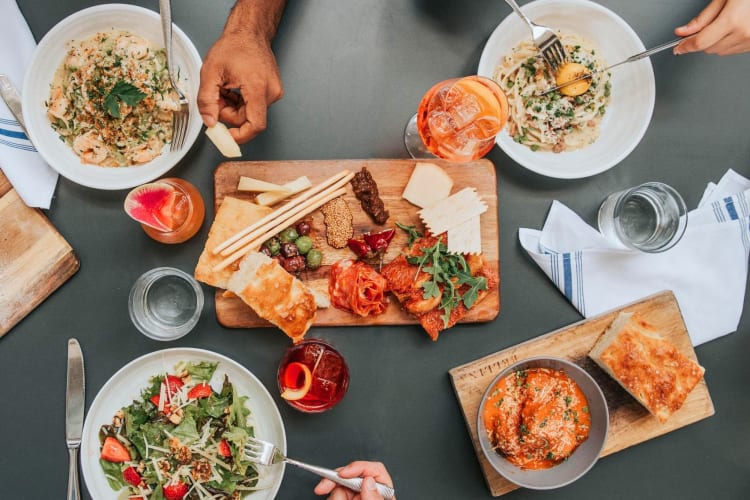 Hands eating from different meals at Ponce City Market in Atlanta