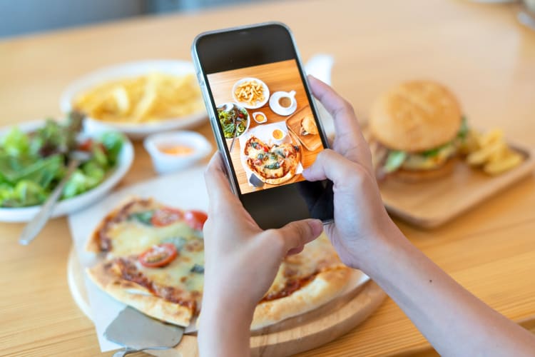 Person's hand holding a phone taking a photo of food