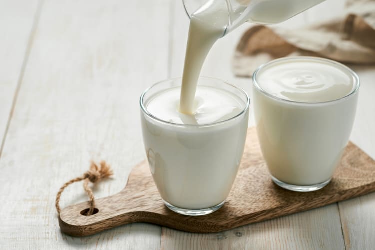 A person pouring kefir into a glass