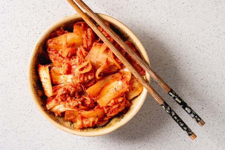 A bowl of kimchi with chopsticks balanced on it