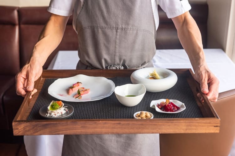 Chef holding a variety of food portions from a tasting menu at Frasca Food and Wine in Boulder