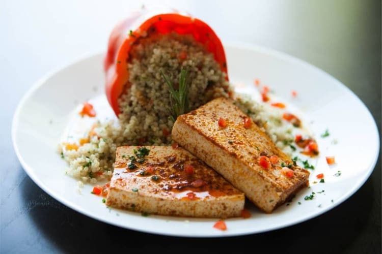 A dish of marinated tofu and quinoa-stuffed red pepper