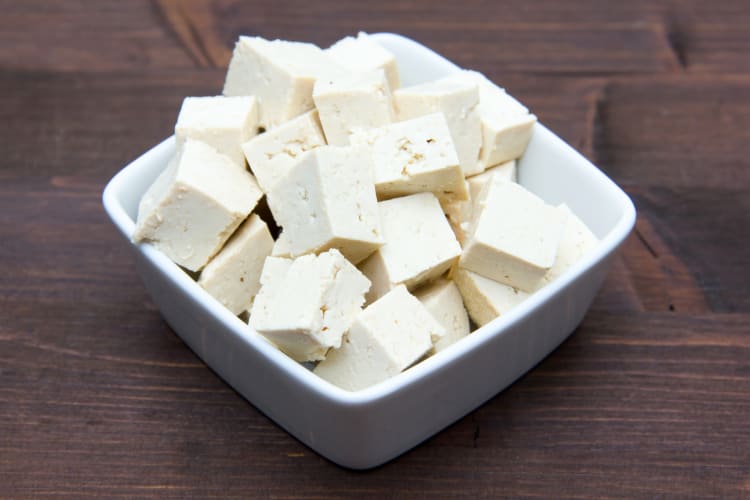 A dish with cubed tofu on a wooden surface