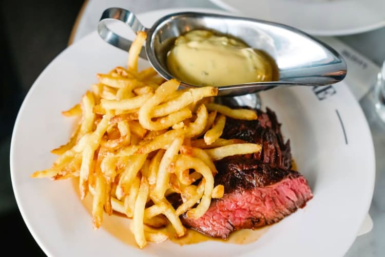 Steak, fries and a jug of sauce on a plate