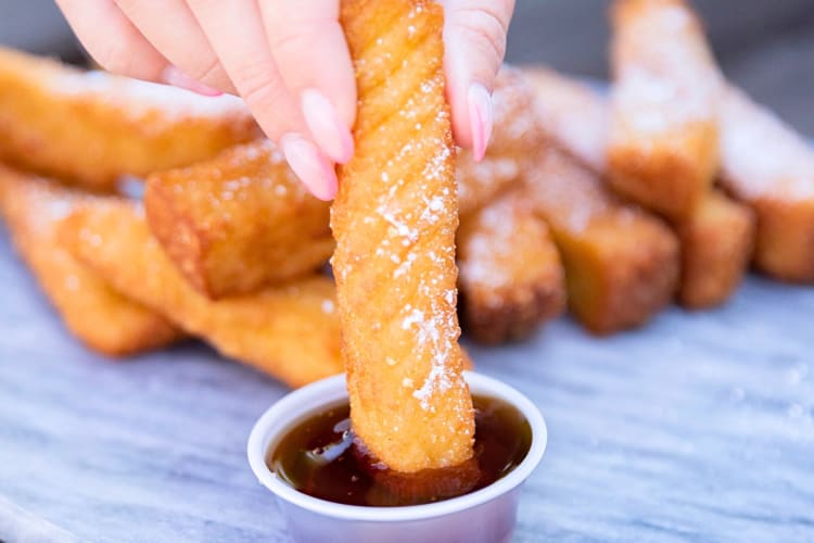 Person's hand dipping a French toast stick into sauce