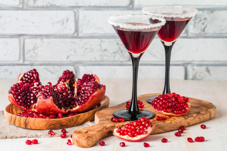 Two pomegranate martinis next to fresh pomegranate 