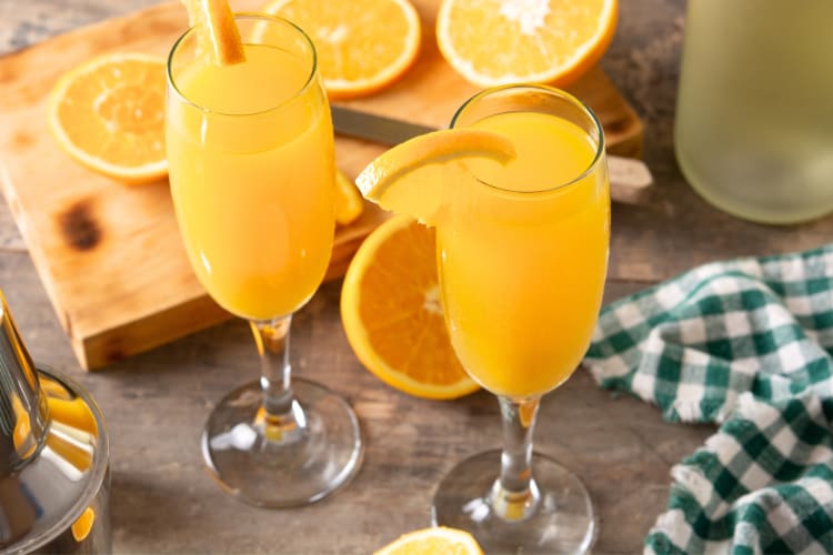 Two Champagne flutes with orange juice mimosas