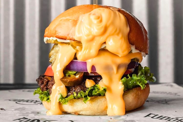 Side-view of a cheeseburger with lots of melted cheese all over it