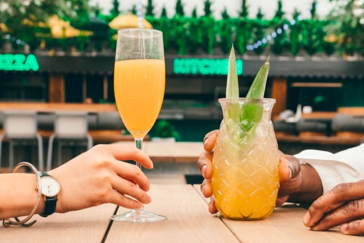 Two people cheersing drinks at a rooftop bar