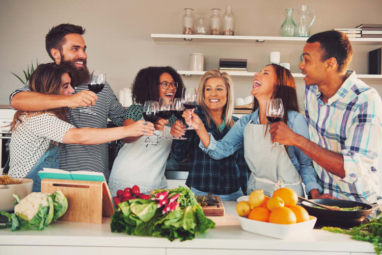 People drinking wine while cooking in a kitchen