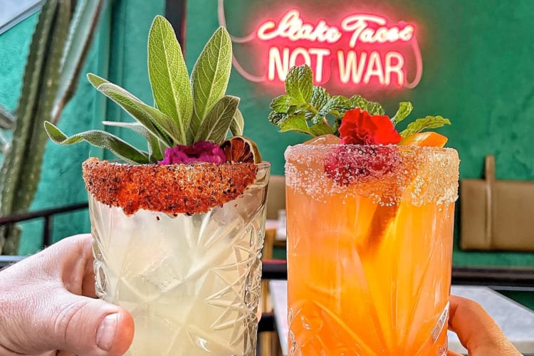 Two people holding colorful, tropical drinks