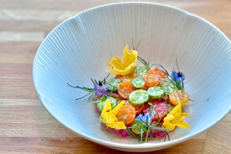 A bowl with cherry tomatoes and edible flowers